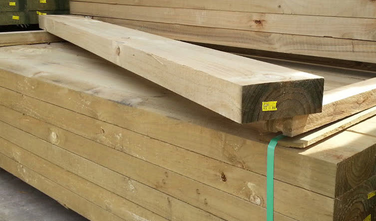 A timber beam on a strapped stack, yellow tag on the end